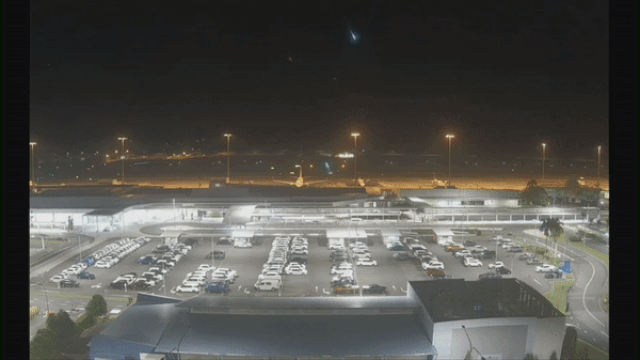 A meteor lights up the night sky with a bright green flash over an Australian airport